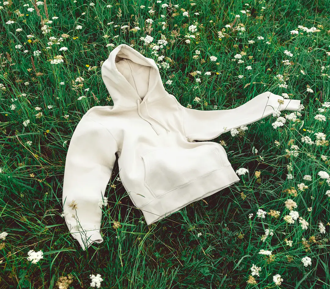 Sustainably made hoodie laid in a wildflower field, chosen for an employee appreciation program
