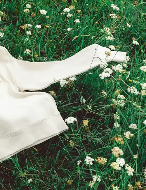 Sustainably made apparel sleeve resting in a wildflower field, chosen for a remote team welcome kit